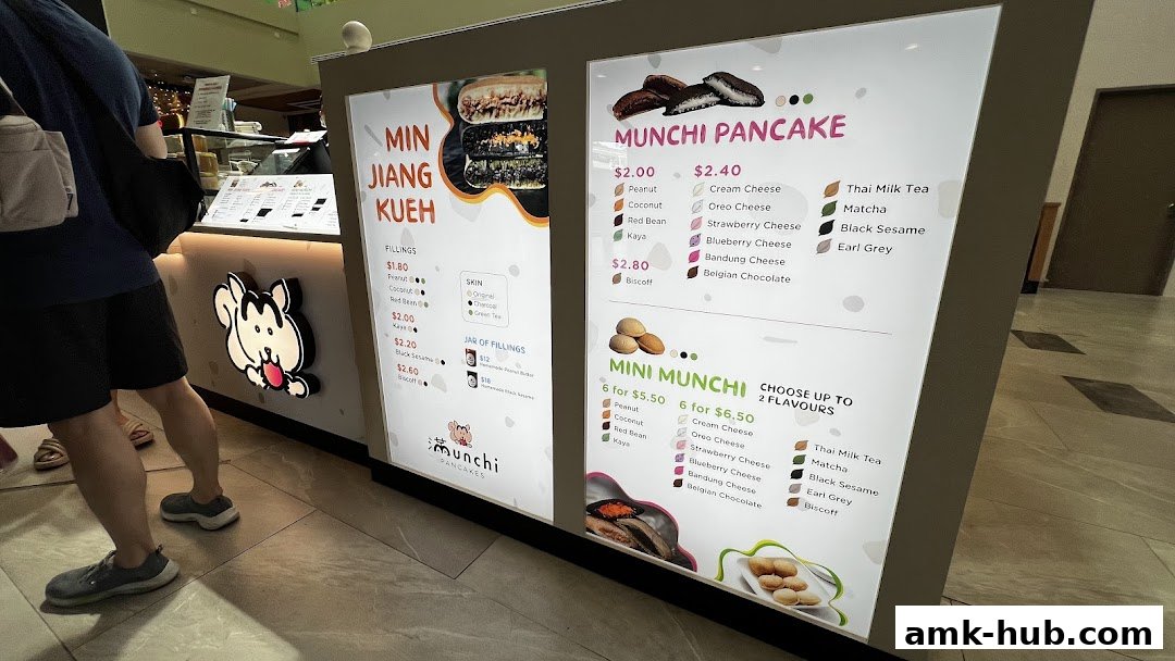 A brightly lit menu board for Munchi Pancakes, showcasing various fillings and mini pancake options.
