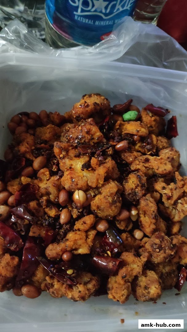 A close-up of a spicy fragrant pot dish with fried chicken, peanuts, and dried chilies.