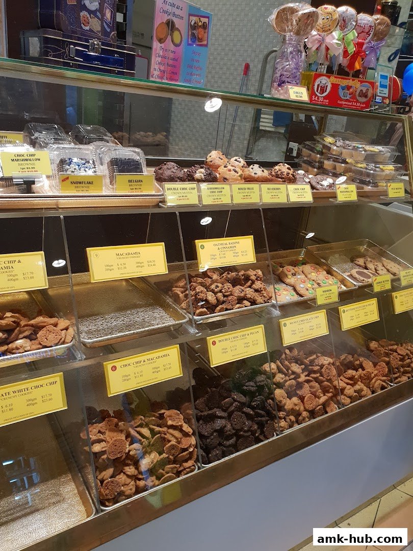A display case filled with various cookies, brownies, muffins, and lollipops from Famous Amos.