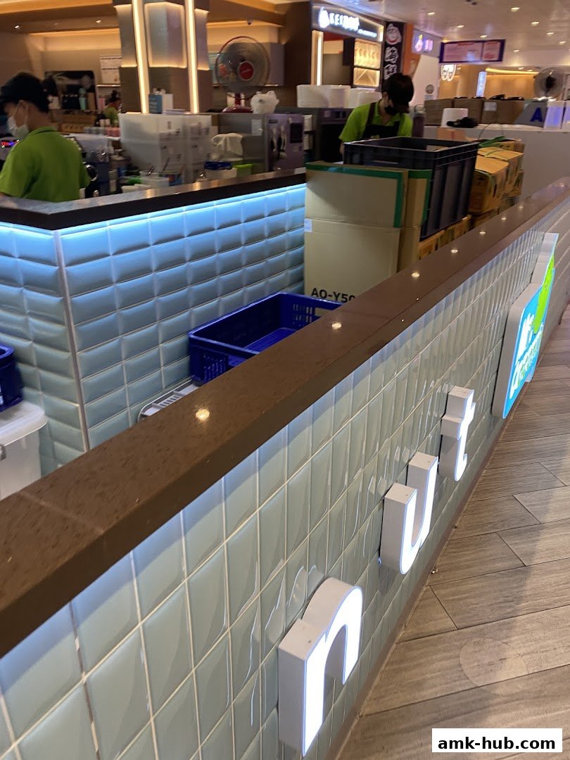 A counter at Mr. Coconut with staff preparing drinks and illuminated signage.