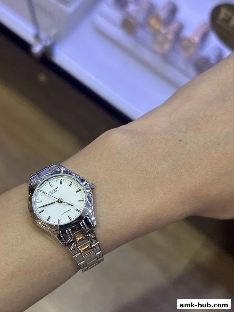 A close-up shot of a person wearing a silver Casio watch with a white dial.