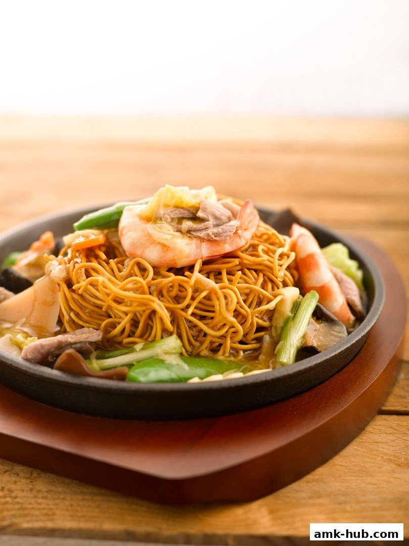 A sizzling hot plate of crispy noodles with shrimp, meat, and vegetables.