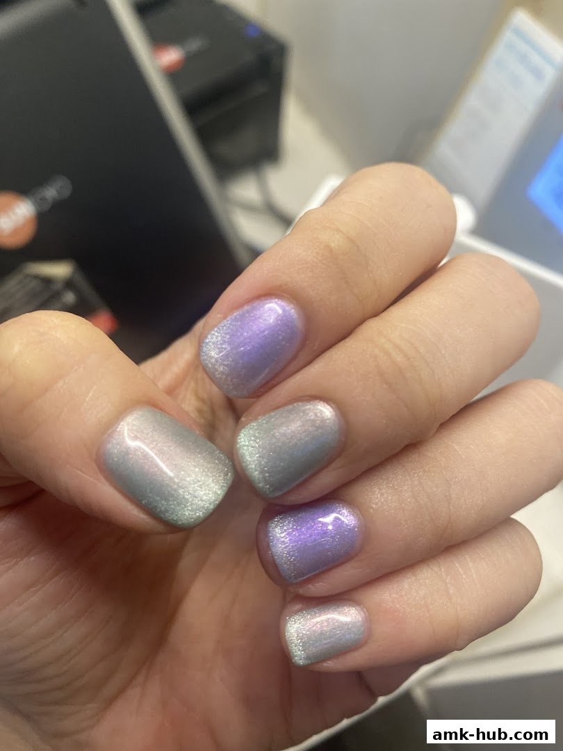 Close-up of a hand with beautifully manicured nails in a shimmering pastel gradient.
