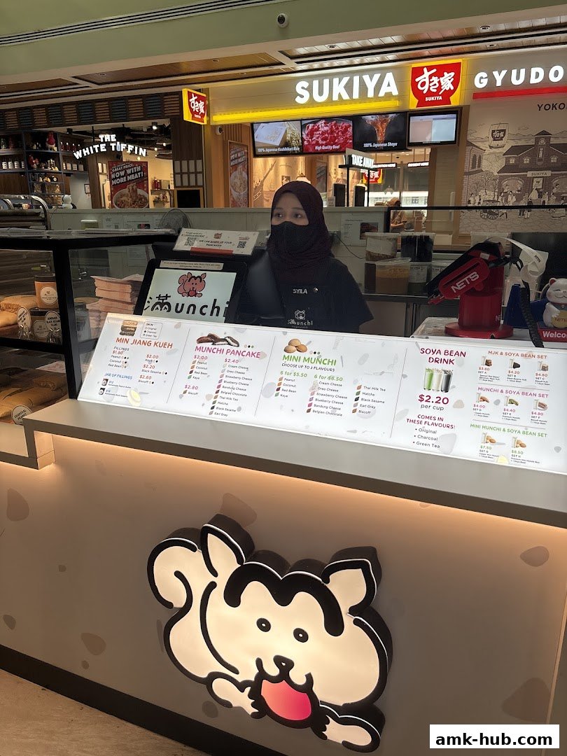A food stall counter with a menu displaying pancakes, mini pancakes, and soya bean drinks.
