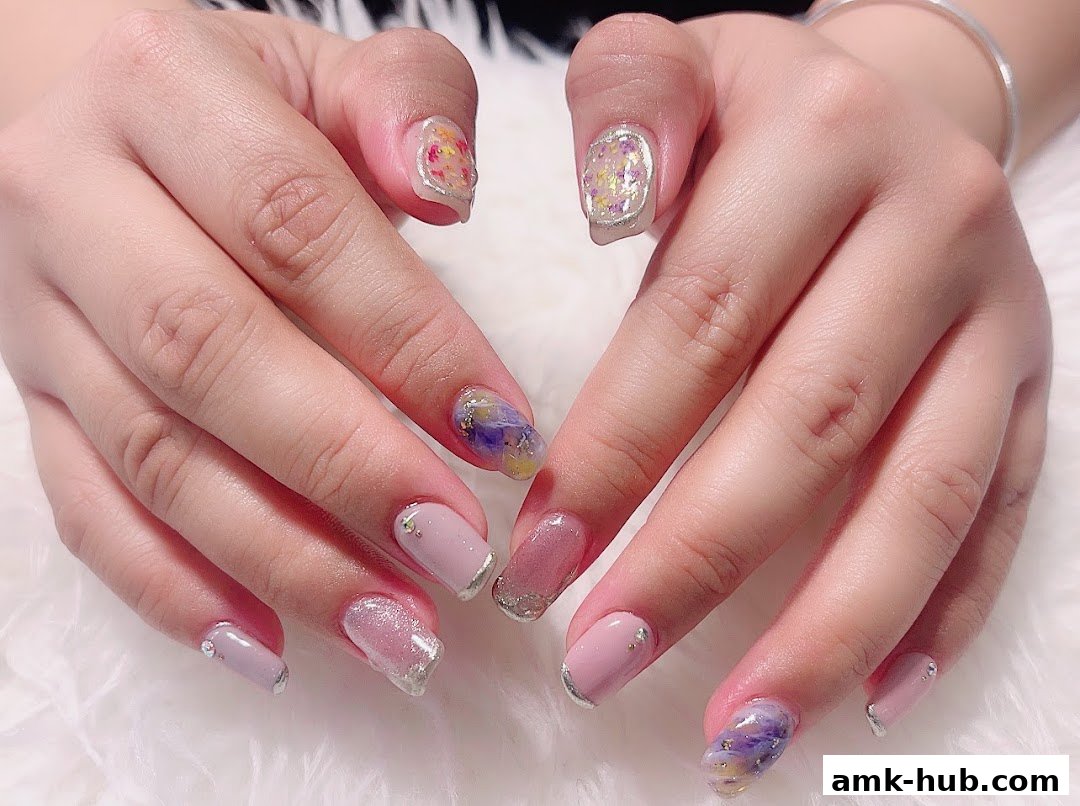 Close-up of hands showcasing beautifully designed nails with floral and glitter accents.