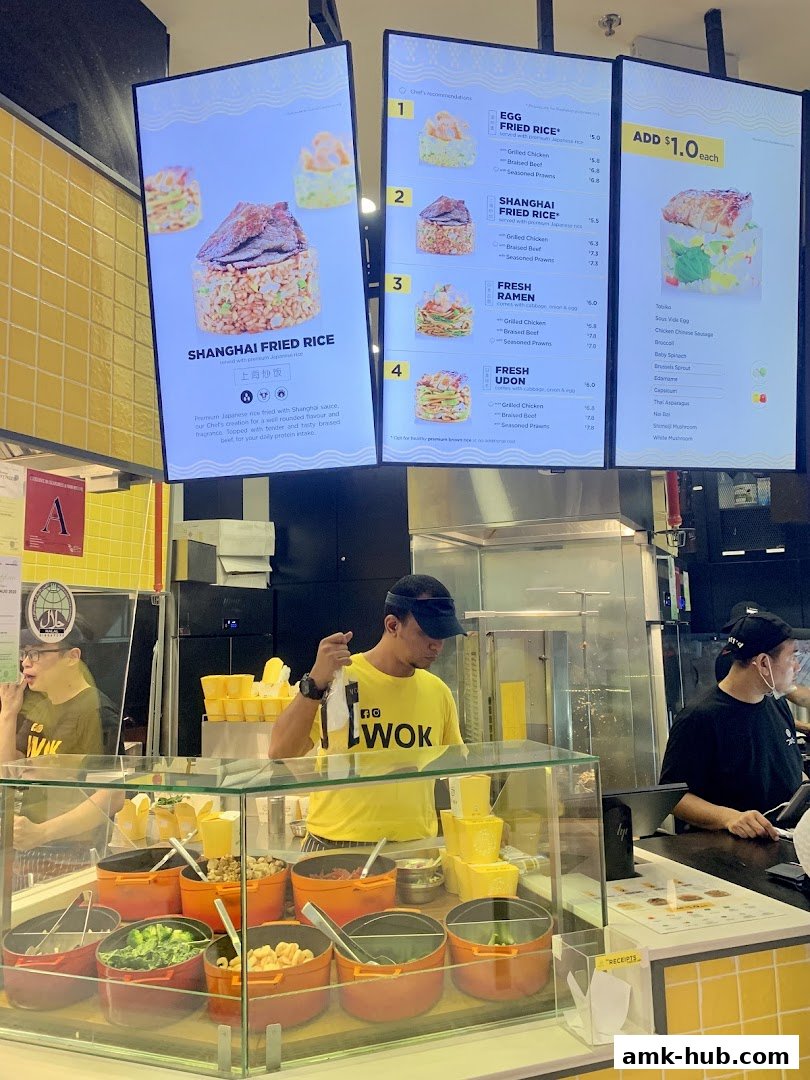 Digital menu boards displaying various rice, ramen, and udon dishes with prices.