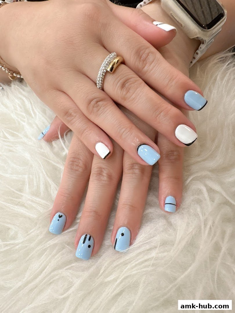 A close-up of a woman's hands with stylish light blue and white nail art.