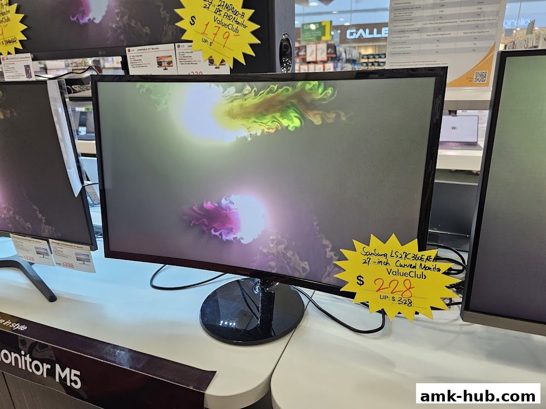 A display of computer monitors, with a focus on a curved Samsung monitor on sale.