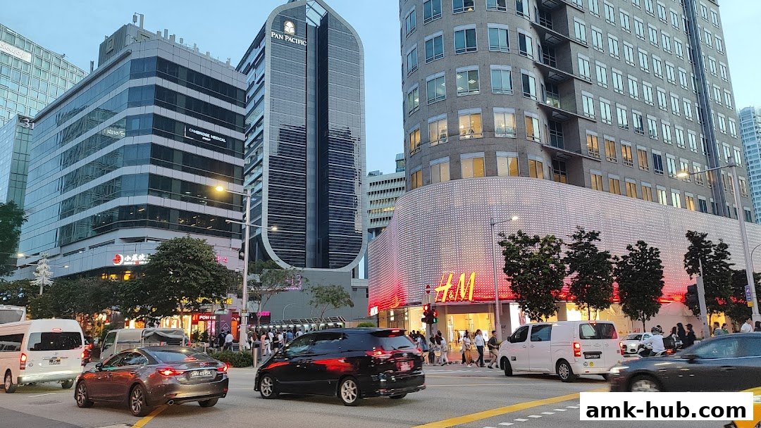 A street view of a busy city intersection with several modern buildings and shops.