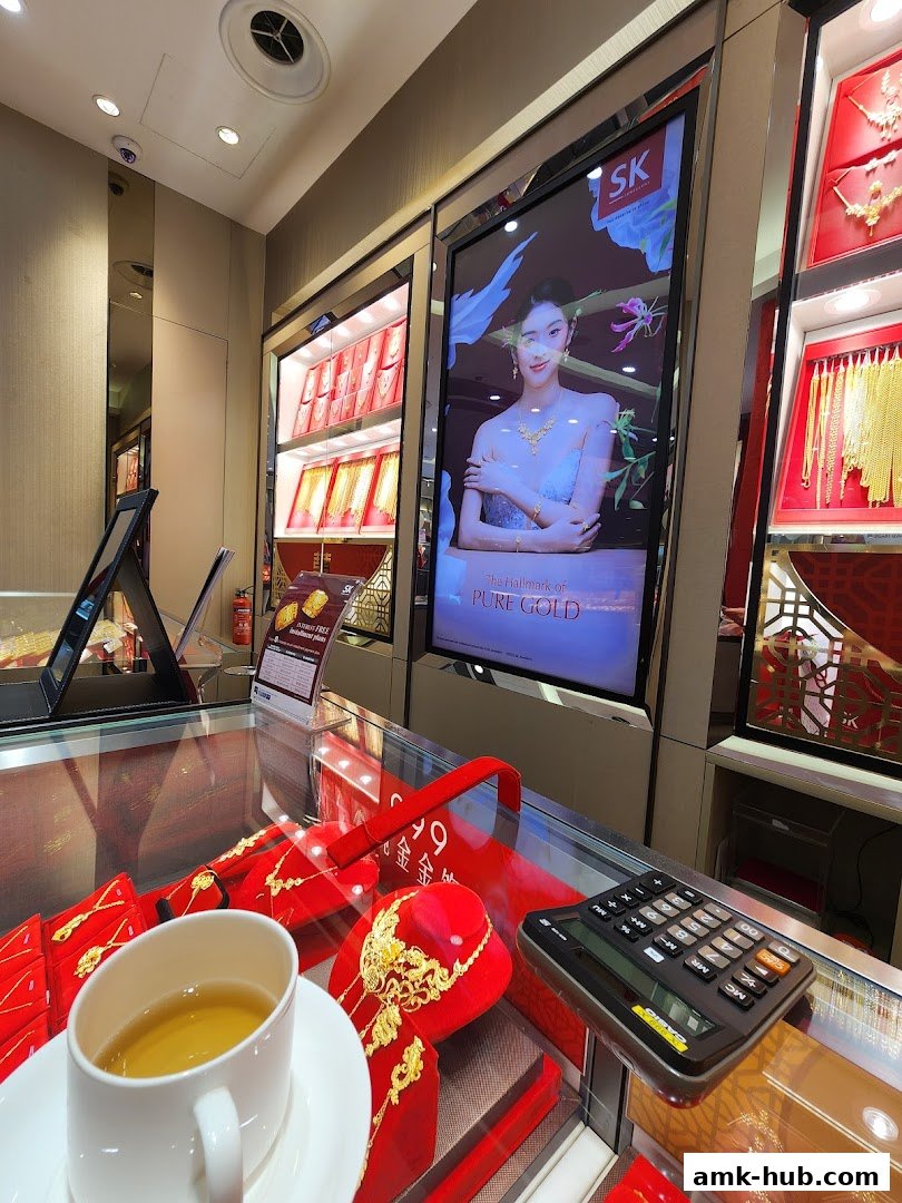 Interior view of a jewelry store with displays of gold necklaces and a promotional screen.