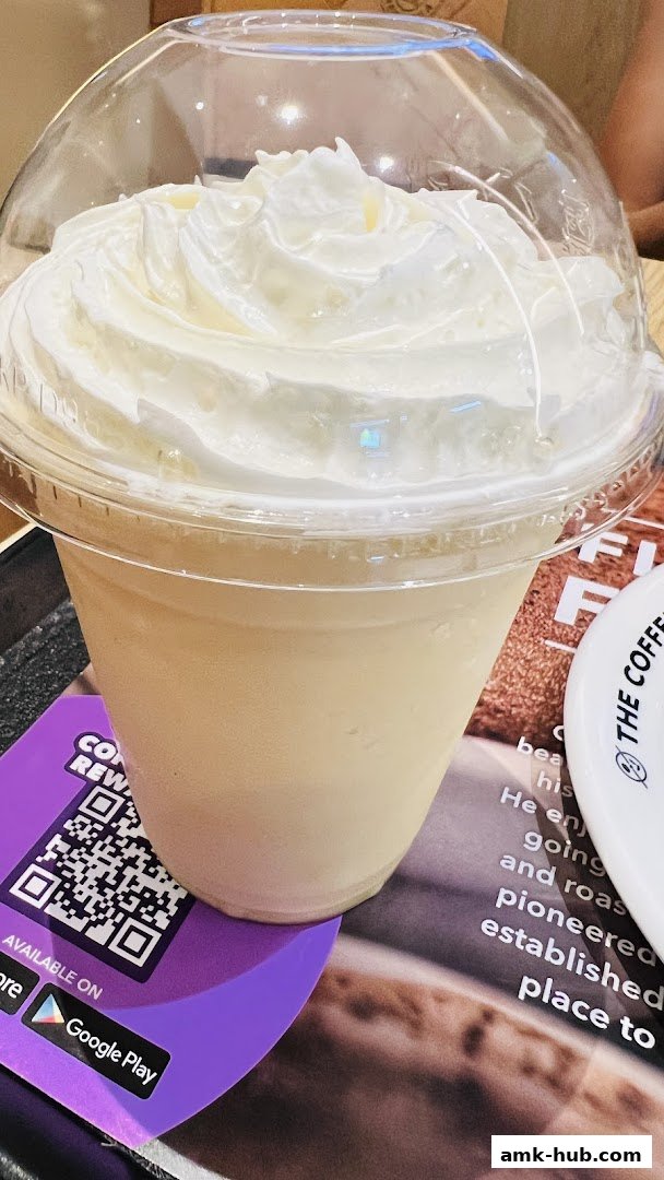 A close-up of a creamy beverage topped with whipped cream in a clear plastic cup.