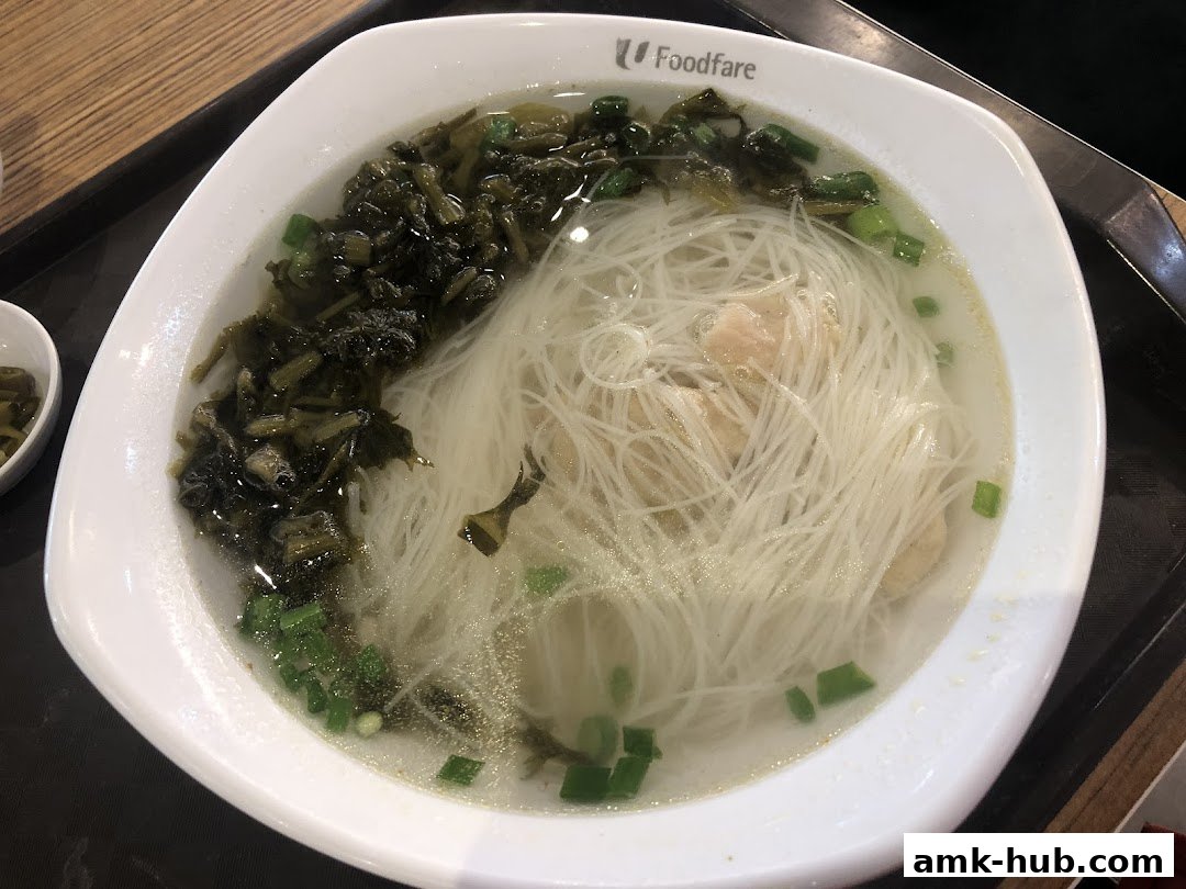 A bowl of rice vermicelli soup with preserved vegetables and chopped scallions.