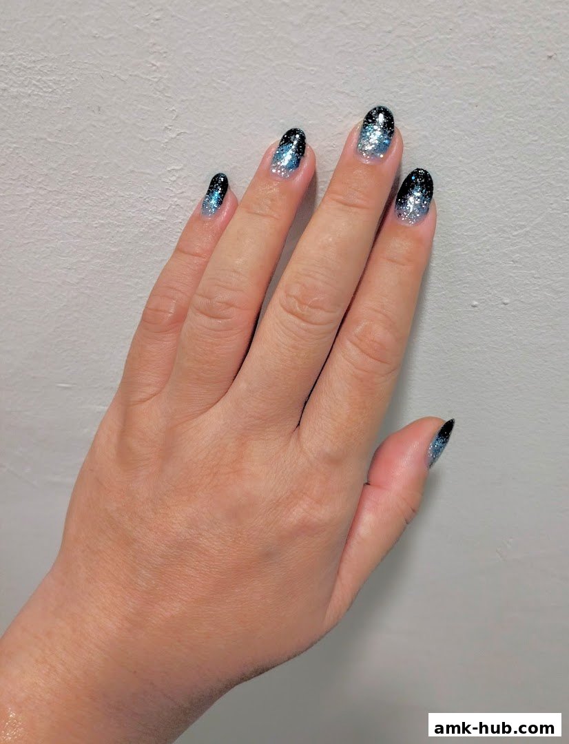 A hand with beautifully manicured nails featuring a glittery ombre design.