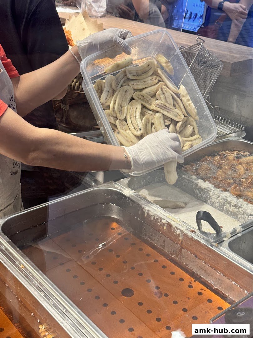 A person in gloves is preparing to fry bananas in a food stall.