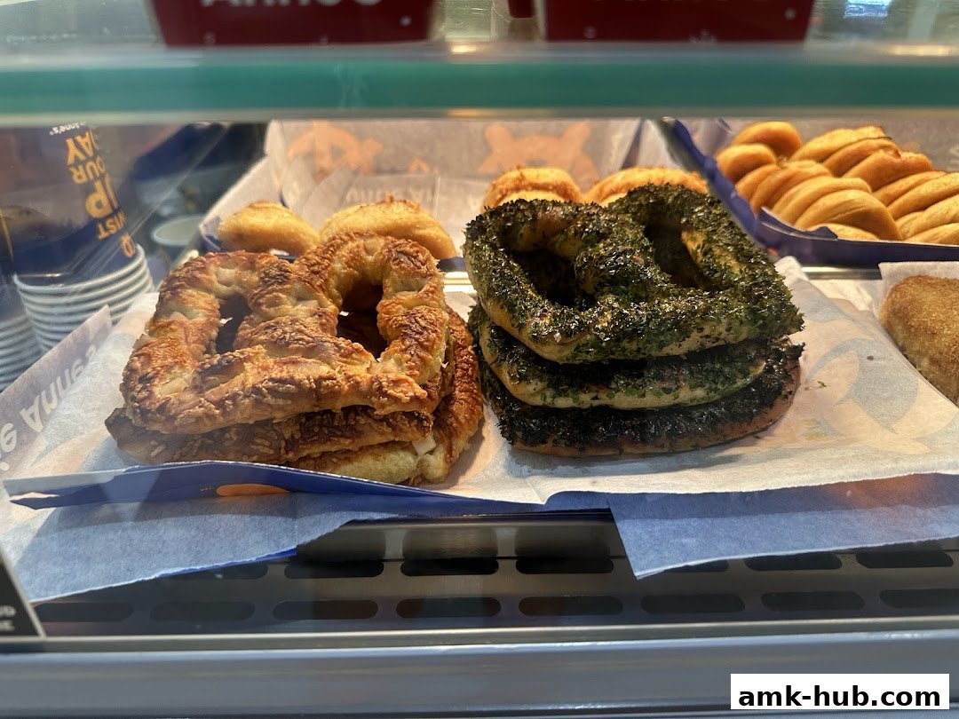 A display case filled with freshly baked pretzels, including cheese and herb varieties.