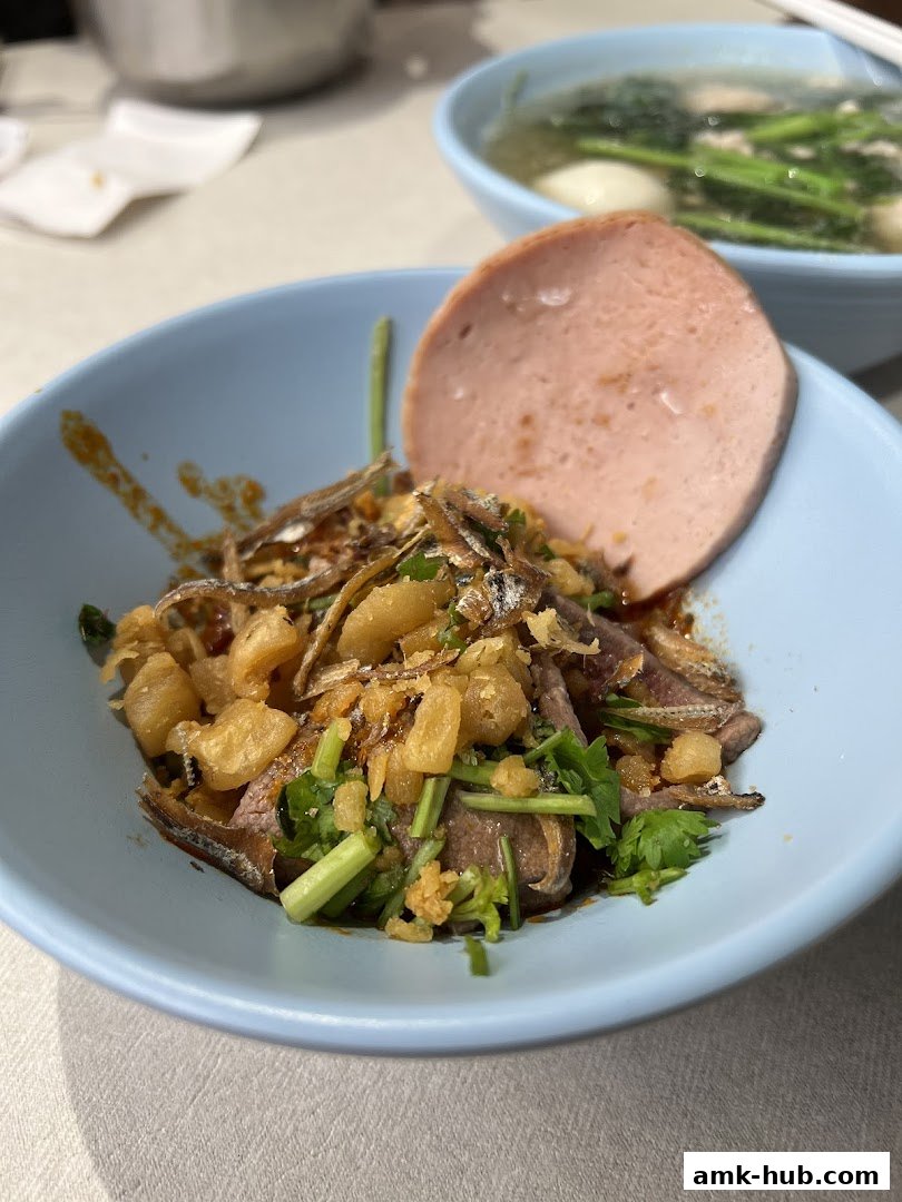 A close-up of a delicious dish with meat, anchovies, and a slice of ham in a blue bowl.