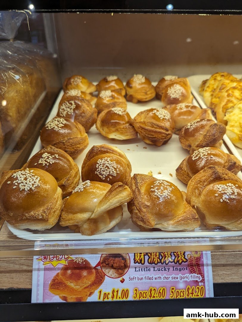 A display of freshly baked buns with sesame seeds and a price tag for 'Little Lucky Ingot'.