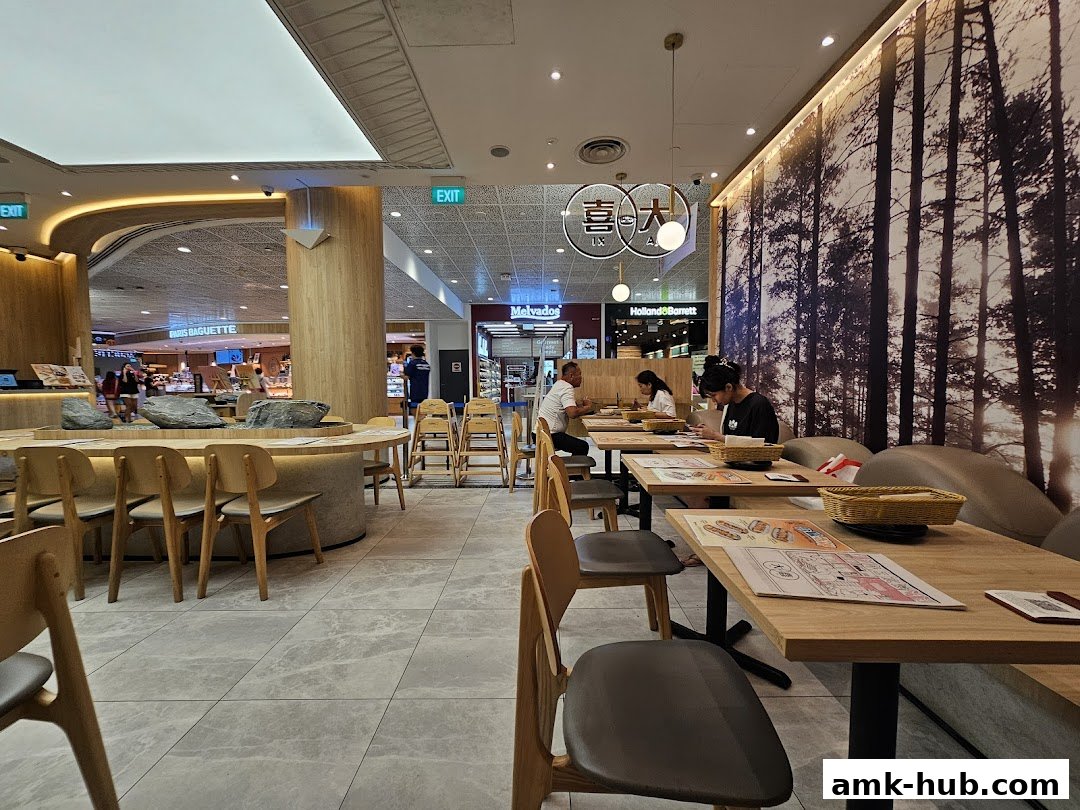Interior view of a restaurant with wooden tables, chairs, and a forest-themed wall.