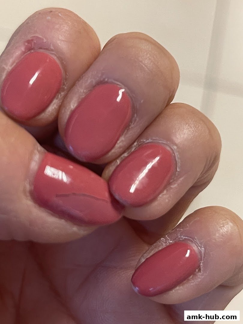 Close-up of a hand with neatly painted pink gel nails.