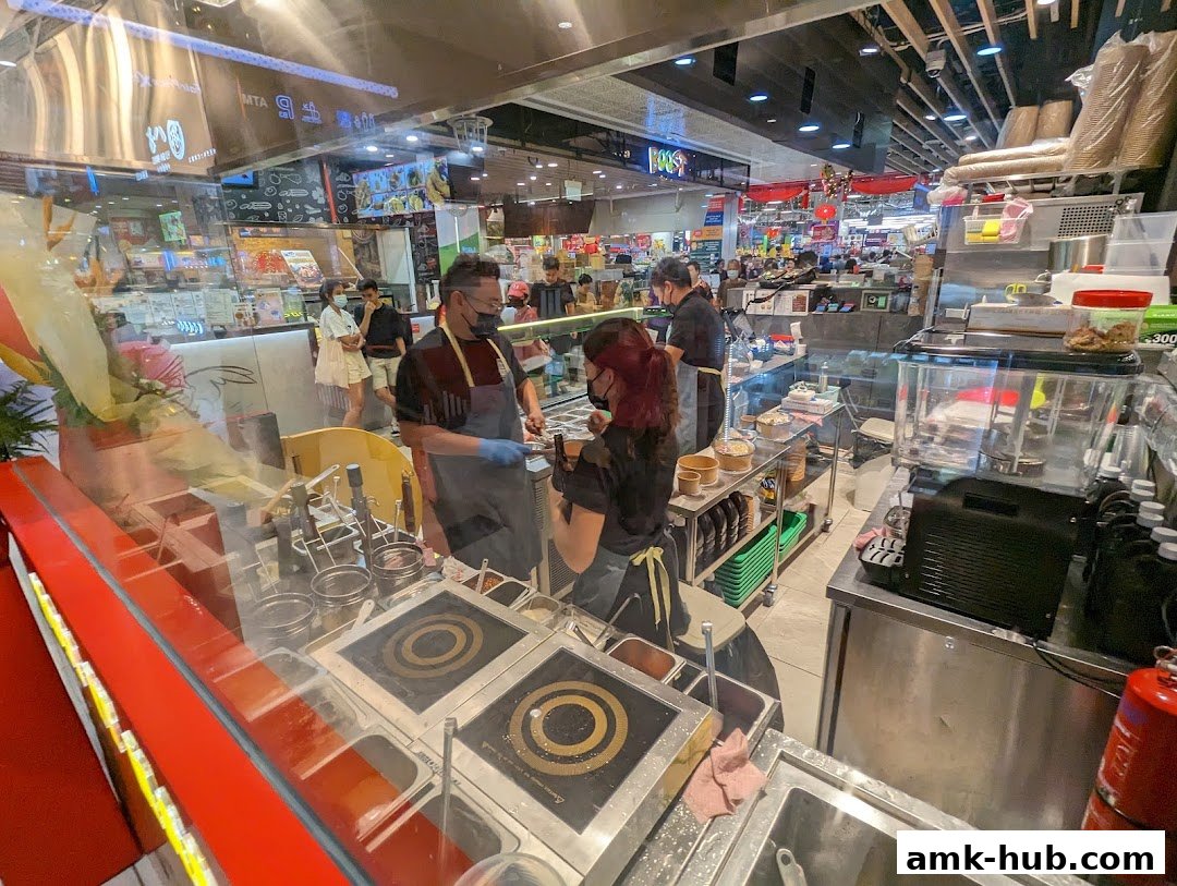 Staff preparing food behind a counter at a pasta shop.