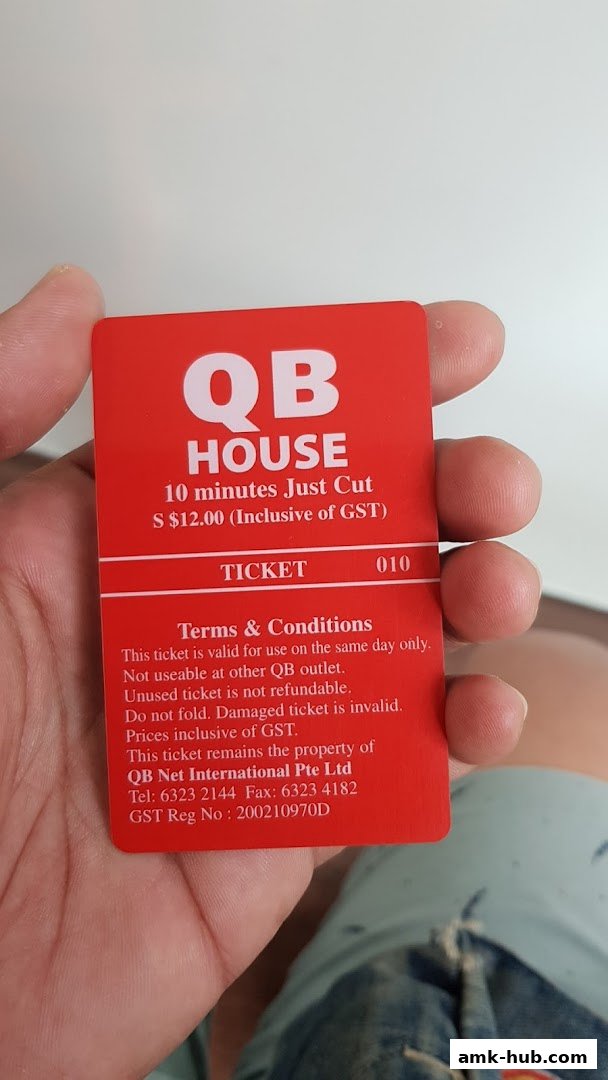 A hand holds a red ticket for QB House offering a 10-minute haircut for $12.