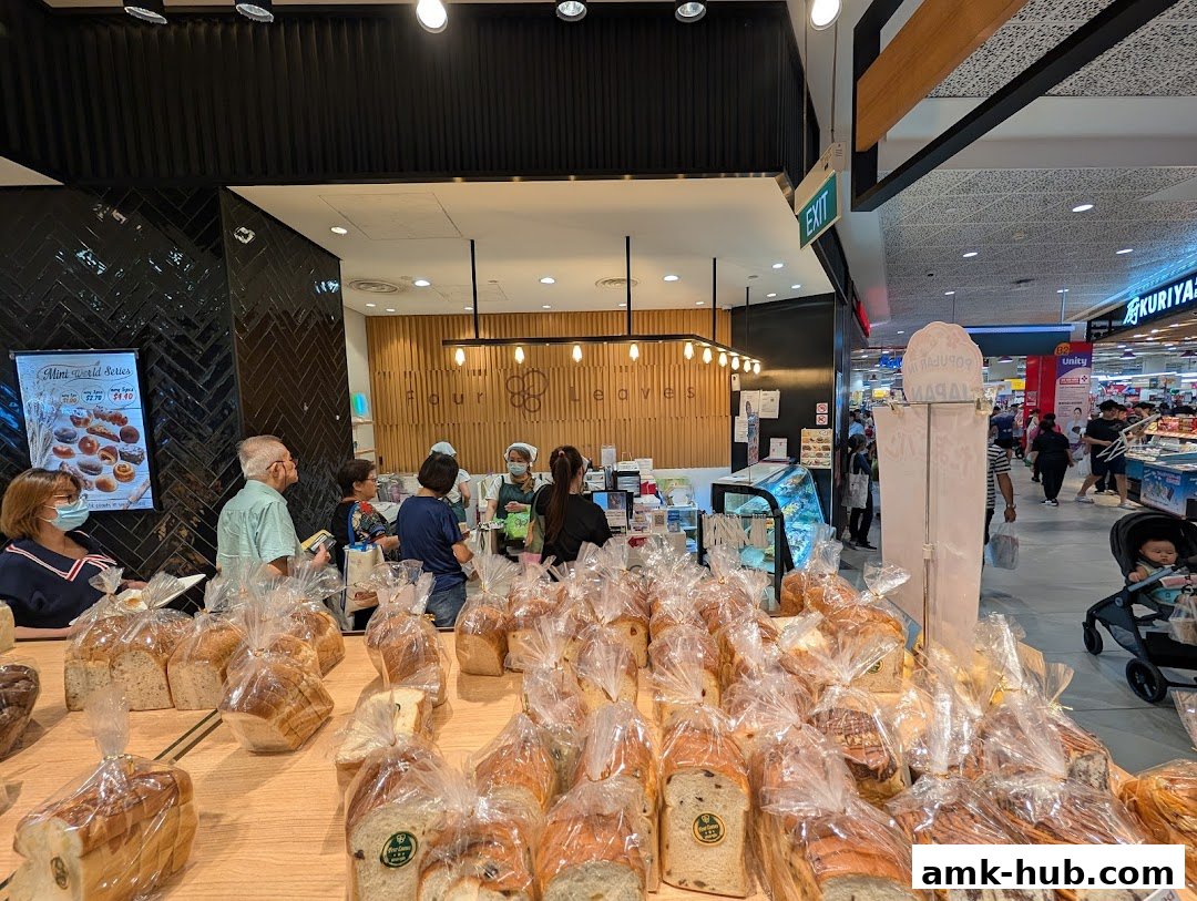A bakery shop with a display of freshly baked bread and pastries, and customers being served.