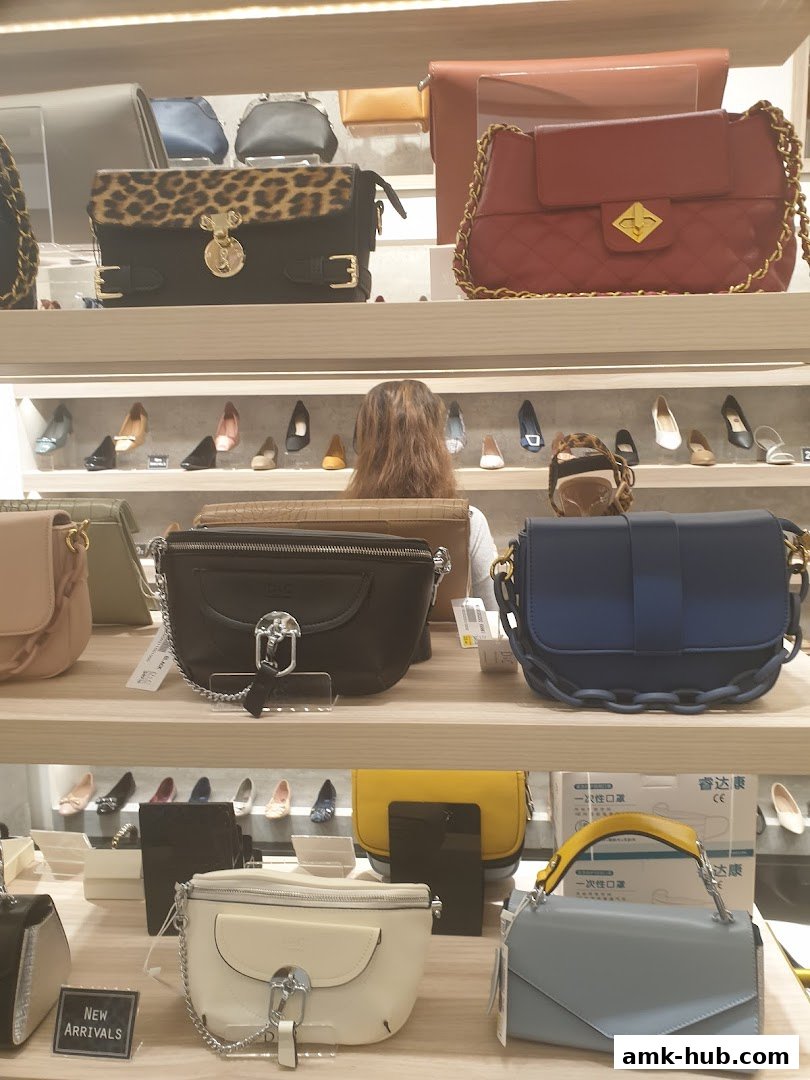 A display of various handbags and shoes on shelves in a retail store.