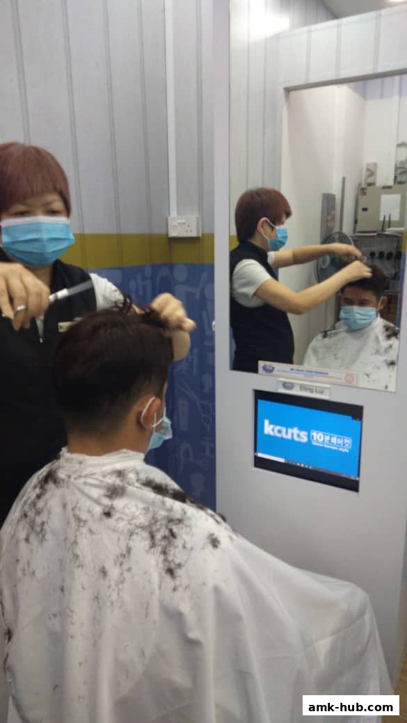 A hairdresser cuts a customer's hair while both wear masks.