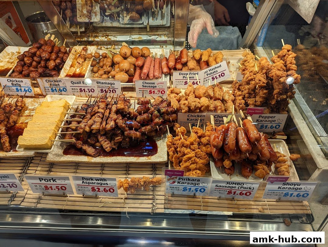 A display of various Japanese skewers and fried items with prices clearly labeled.