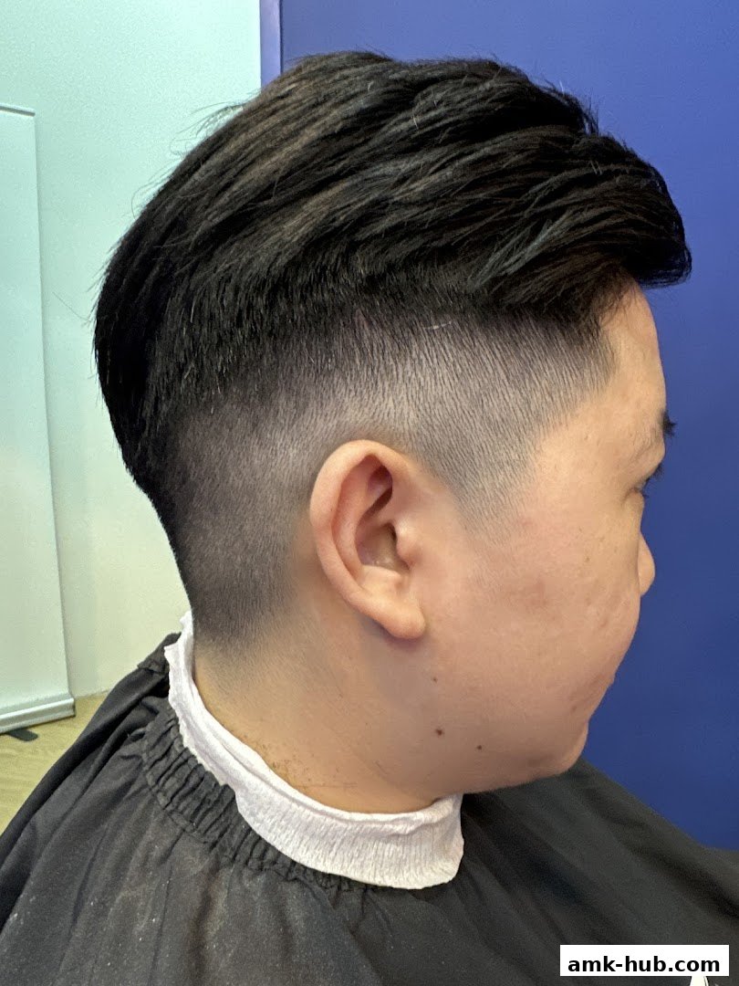 A person with a stylish fade haircut and a barber cape.