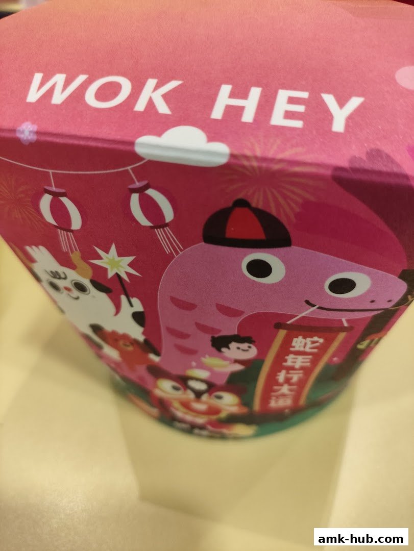 A close-up of a pink Wok Hey takeaway box with cartoon characters and Chinese text.