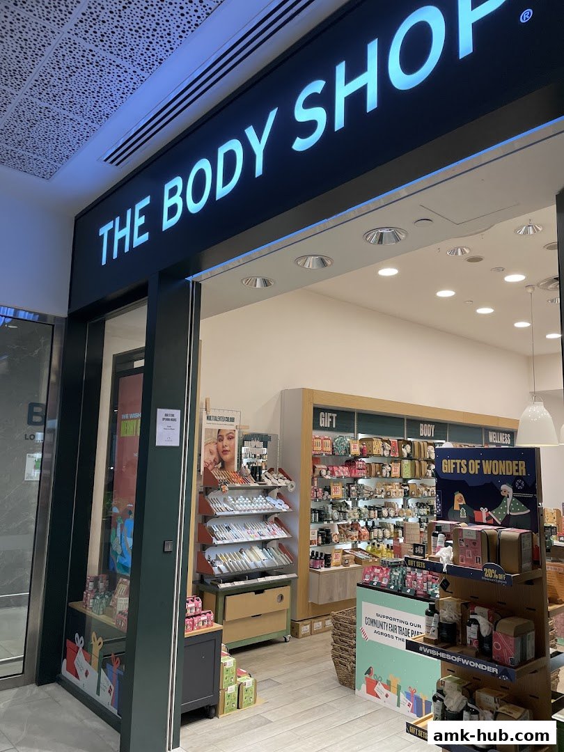 The Body Shop storefront with illuminated signage and displays of gifts and beauty products.
