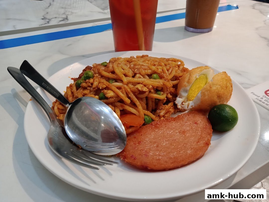 A plate of noodles with fried egg, luncheon meat, and lime, served with drinks.