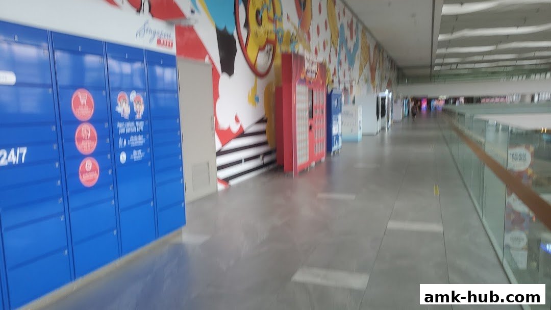 A row of blue parcel lockers with colorful artwork on the wall behind them.