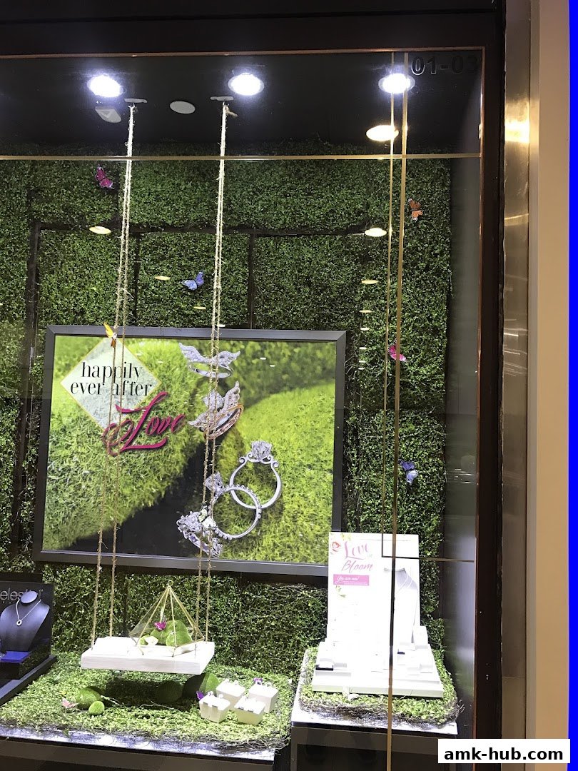 A jewelry shop window display featuring rings, necklaces, and a 'happily ever after' theme.