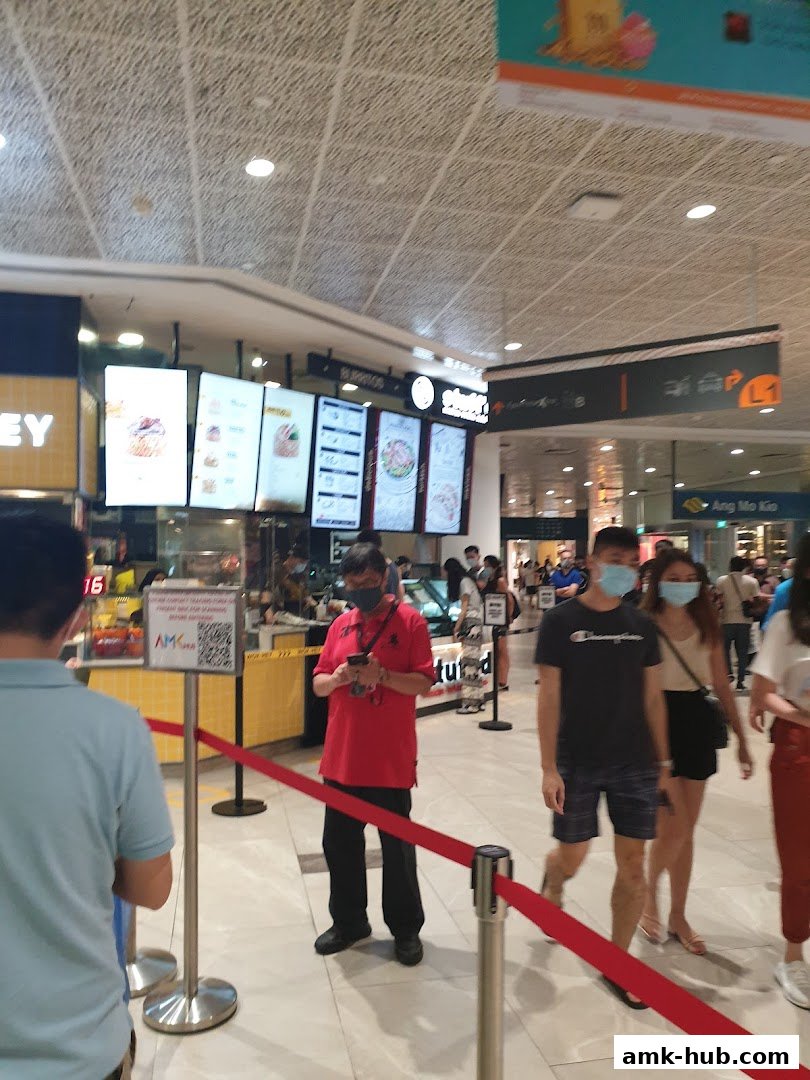 People queuing at WOK HEY AMK Hub with illuminated menu boards visible.
