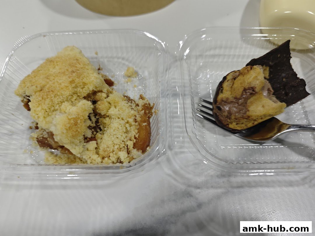 Two plastic containers hold desserts: one with apple strudel and the other with a chocolate cream puff.