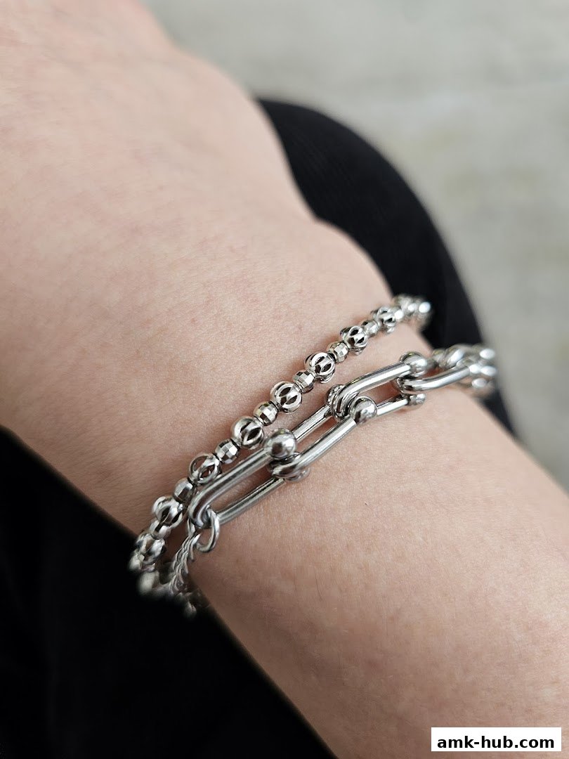 Close-up of two silver bracelets on a person's wrist.