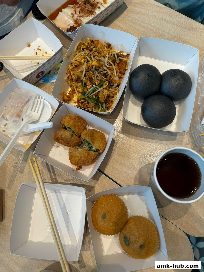 A spread of dim sum dishes including fried items, buns, and tea on a table.