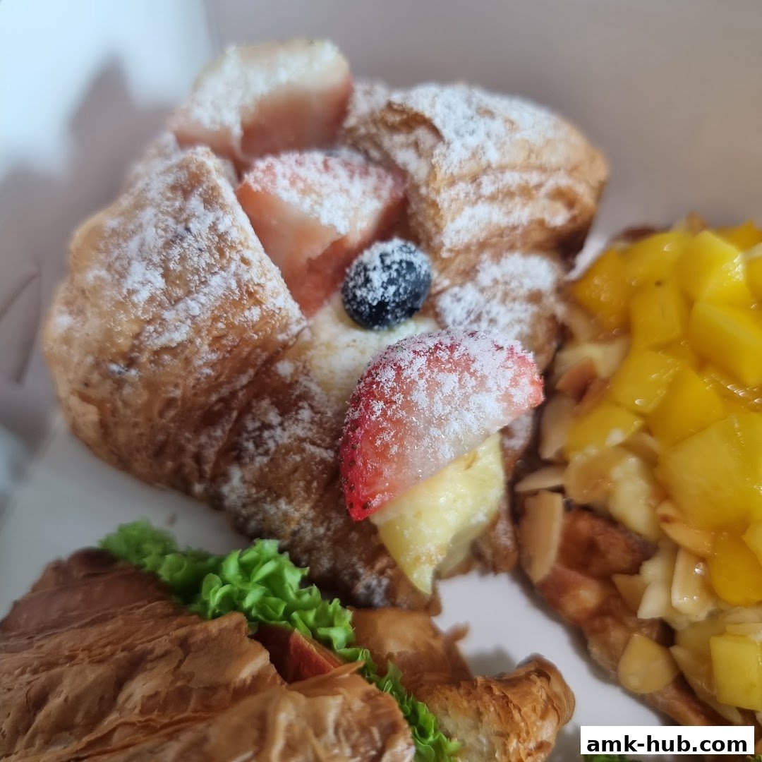 A close-up of assorted pastries, including fruit-topped danishes and a sandwich.