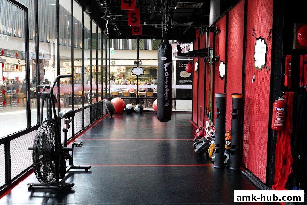 Interior view of a modern gym with boxing equipment and cardio machines.