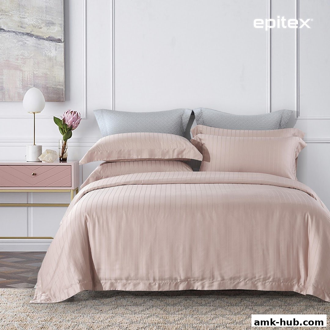 A neatly made bed with pink striped bedding and grey pillows, next to a pink nightstand.