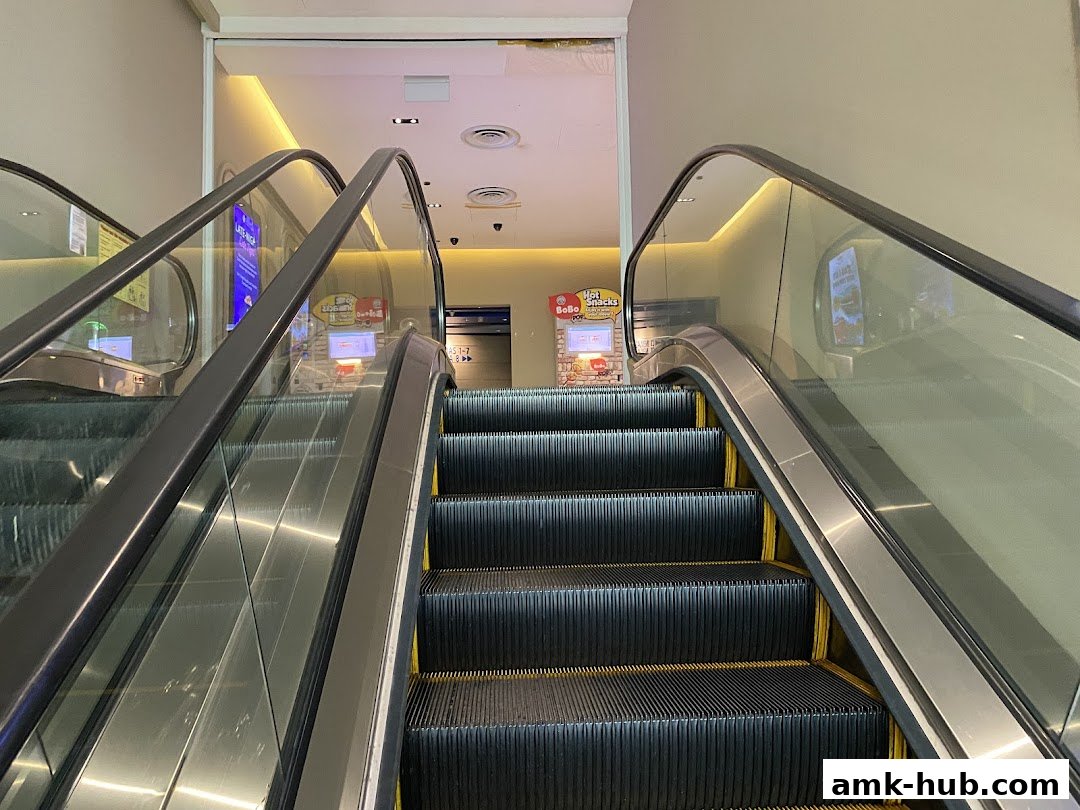 Escalators leading up to a brightly lit area with vending machines.