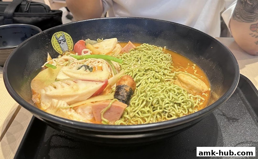 A close-up of a steaming bowl of Mala Tang with green noodles and various toppings.