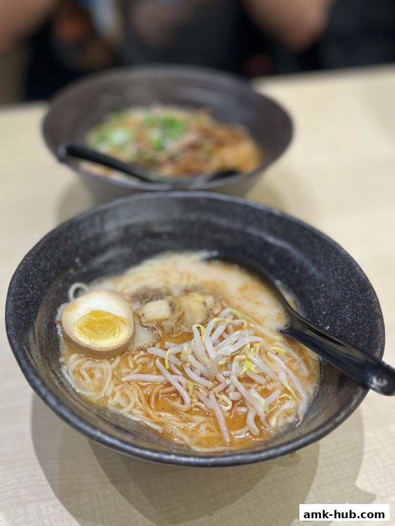 Two bowls of delicious ramen, one in focus with egg, pork, and bean sprouts.