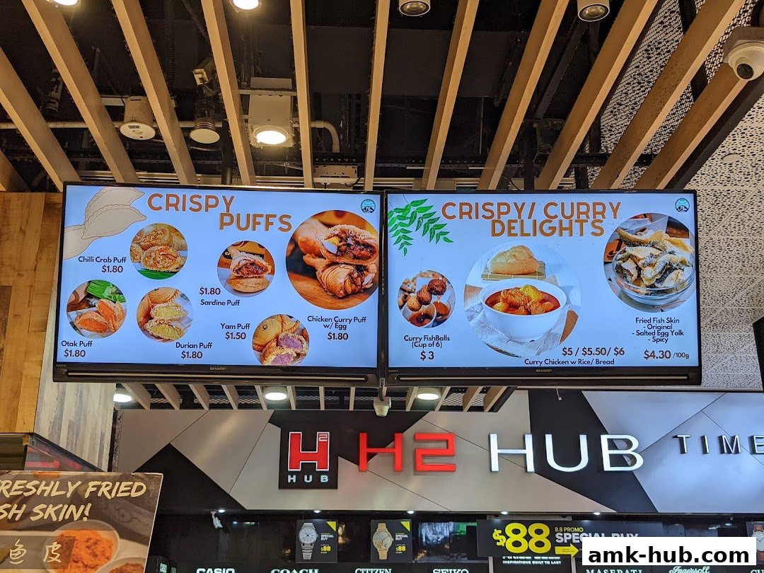 A digital menu board displaying various crispy puffs and curry delights with prices.