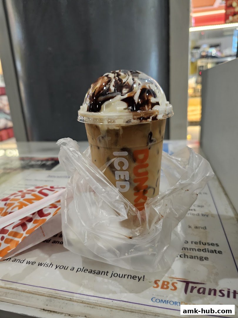 A close-up of a Dunkin' Donuts iced coffee with whipped cream and chocolate drizzle.