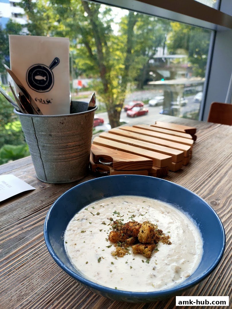 A bowl of creamy soup with croutons and herbs on a wooden table at Fish Co.