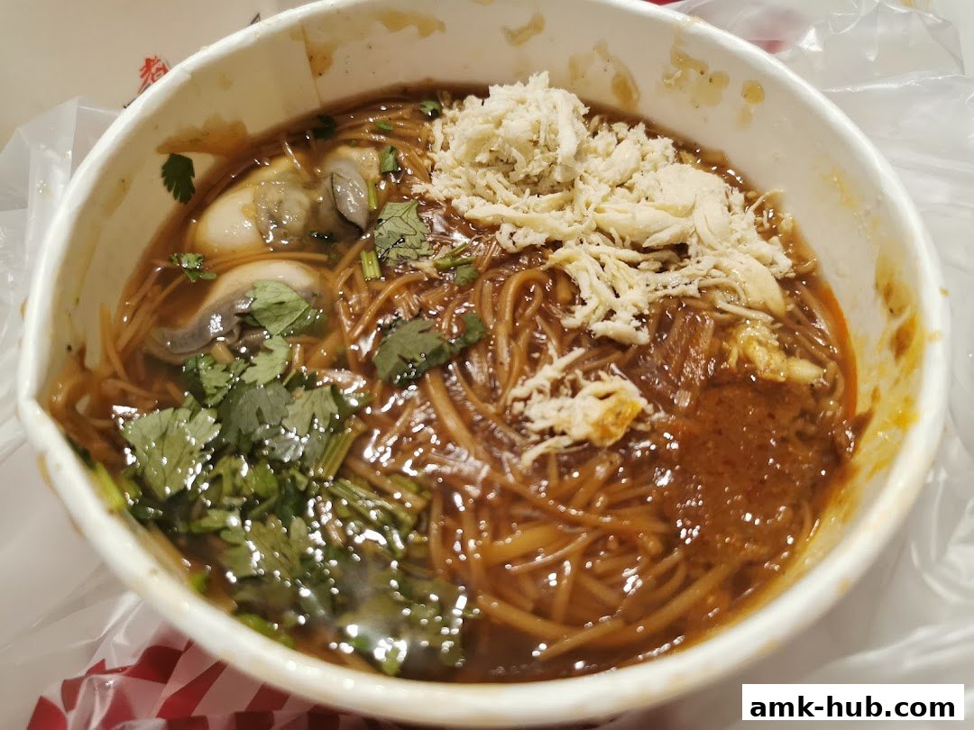 A close-up of a bowl of oyster mee sua with shredded chicken and cilantro.