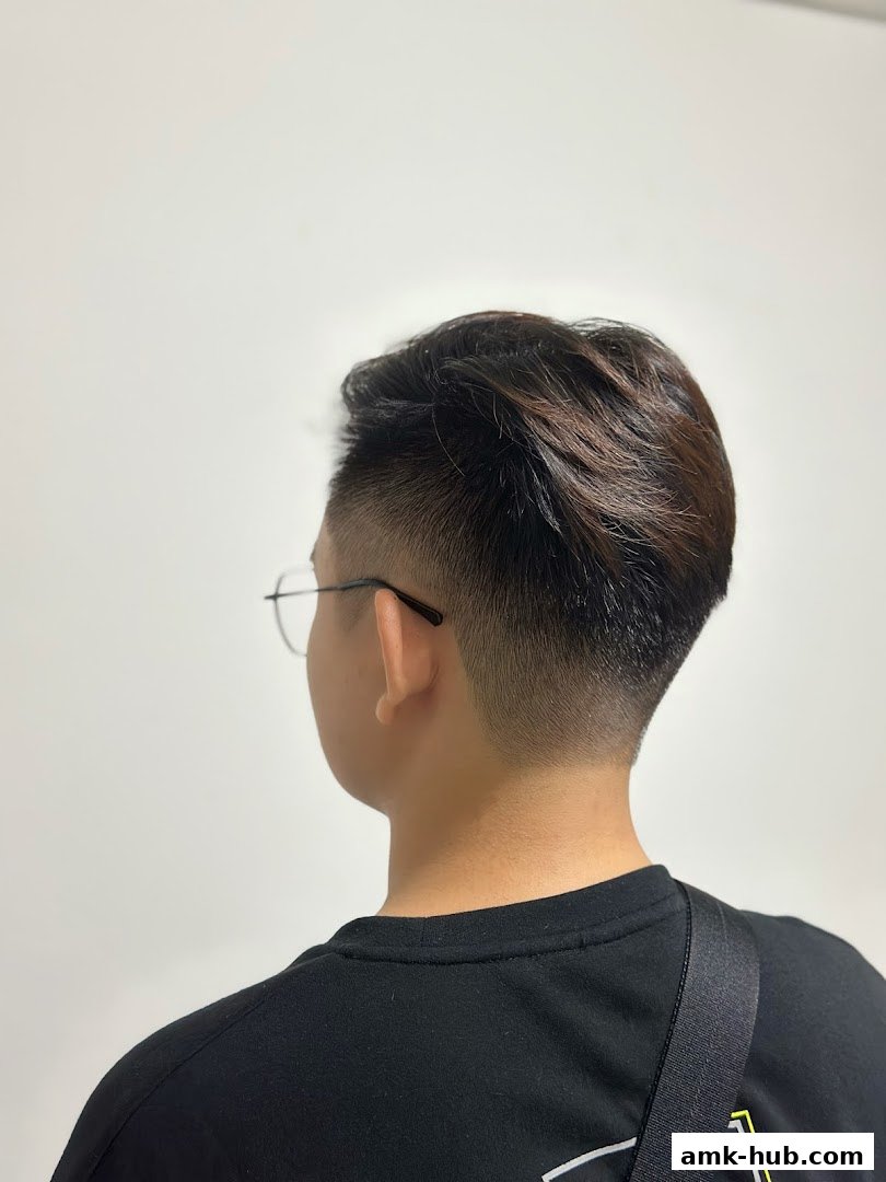 A person with a stylish fade haircut and glasses, viewed from the back.